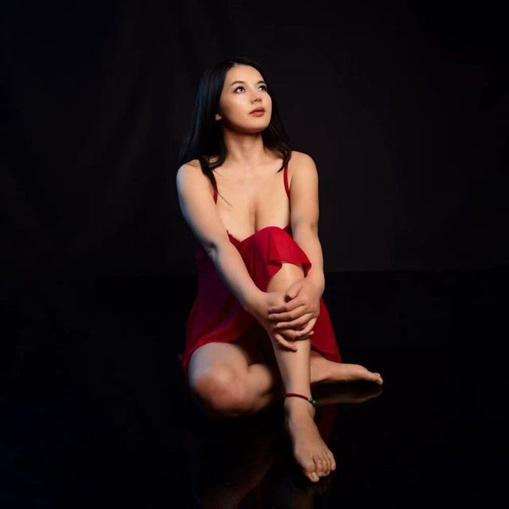 Cherry Red seated in red against a dark studio background