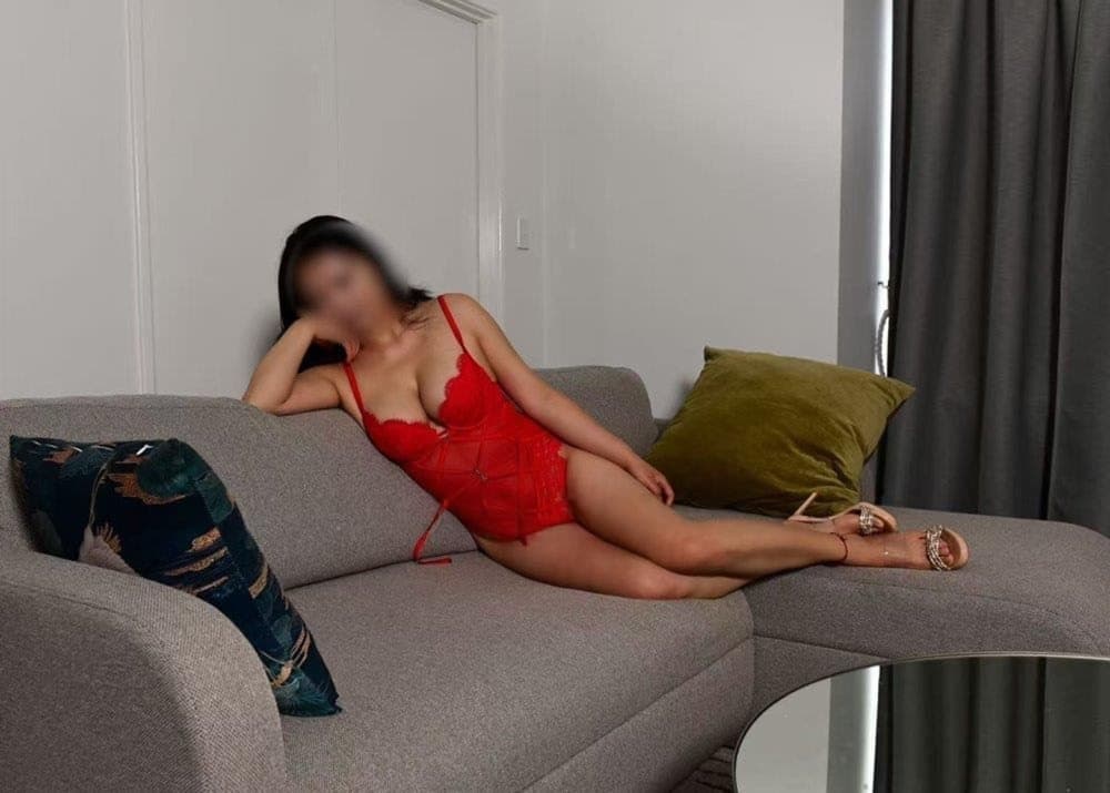 Cherry Red reclining in red with a softly obscured face